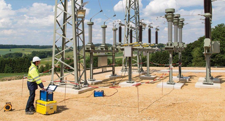 Engineer performing connection and testing work inside a red-roof prefabricated substation